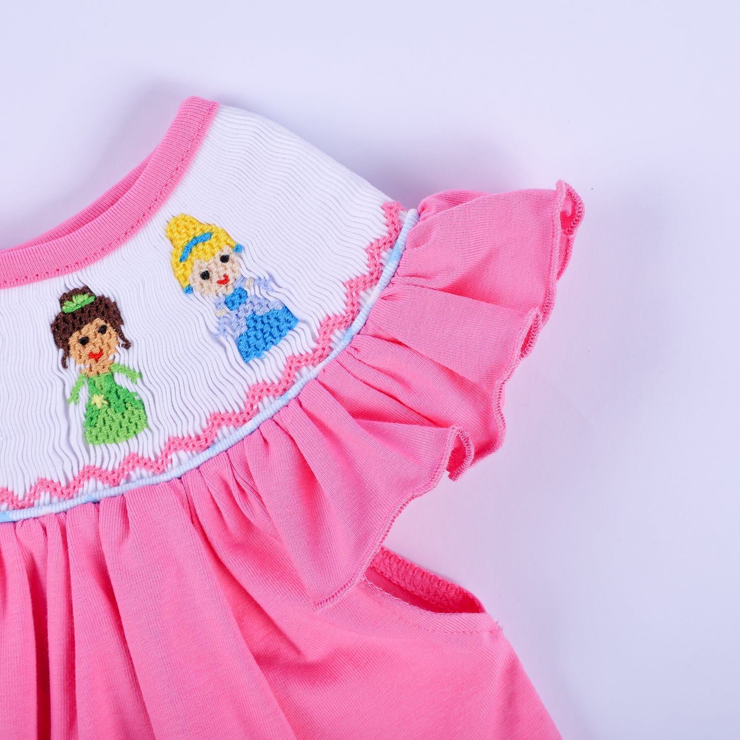 Detailed view of flutter ruffle sleeve and hand-embroidered princess collar on pink smocked baby top.