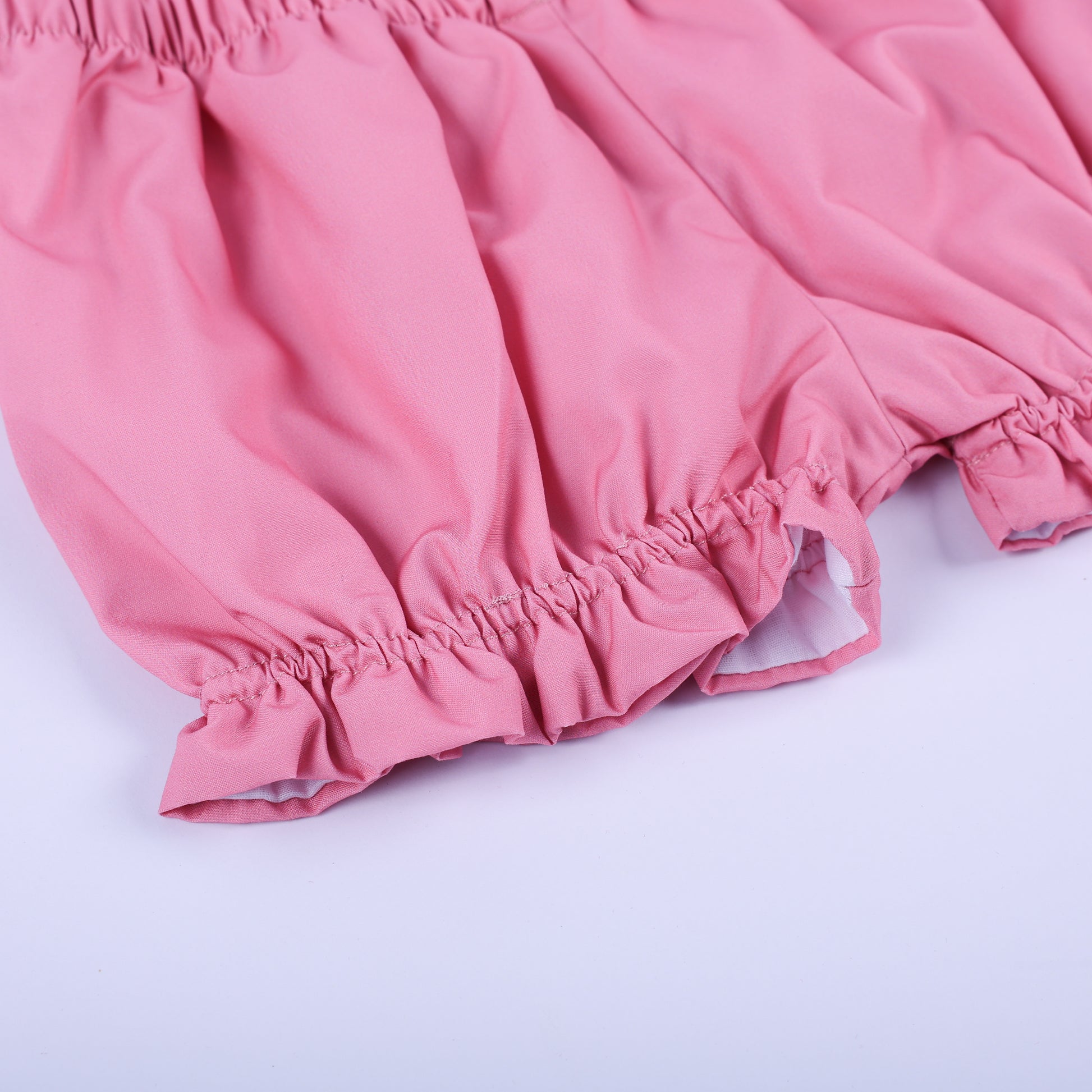 Detailed view of the solid pink ruffle bloomers with gentle elastic leg openings from the birthday girl outfit set.