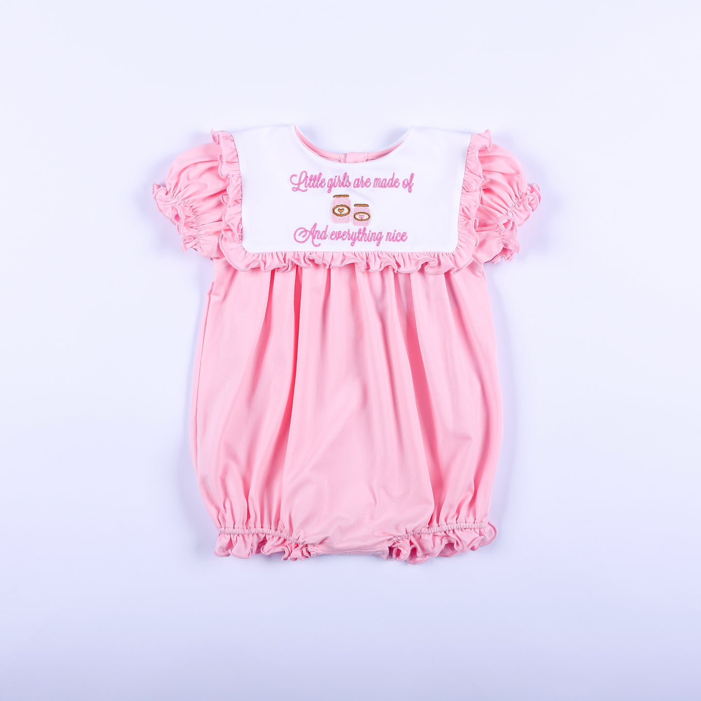 Pink embroidered baby girl bubble romper with white ruffled bib collar reading sugar and spice and everything nice.