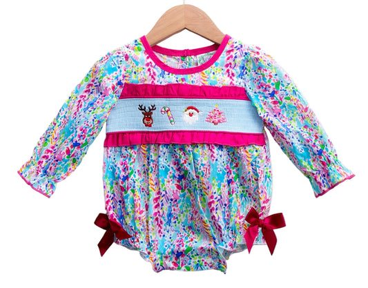 Pink tropical print long-sleeve smocked bubble. Smocking shows a reindeer, candy cane, Santa, and pink tree.