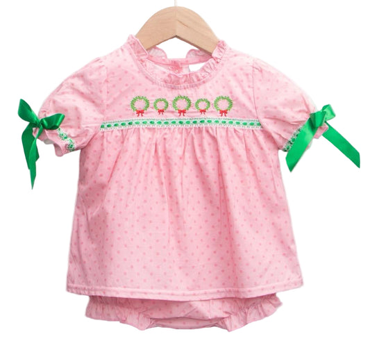 Pink mini-dot woven bubble dress on a hanger, featuring five embroidered Christmas wreaths and green sleeve bows.