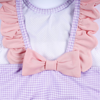 Close-up back view of purple gingham smocked swim top showing ruffled shoulder straps and pink bow accent.