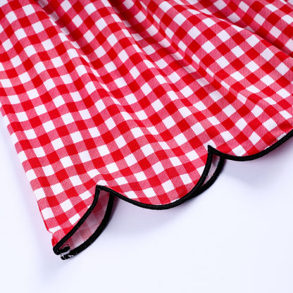 Detail of the black trimmed scalloped hemline on a classic red gingham hand smocked dress for children.