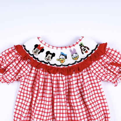 Front view of hand-smocked white collar with hand-embroidered character faces and red ruffle trim on baby bubble.
