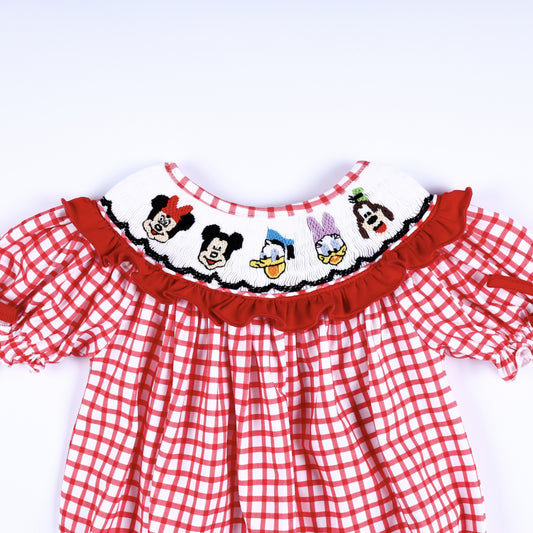 Front view of hand-smocked white collar with hand-embroidered character faces and red ruffle trim on baby bubble.