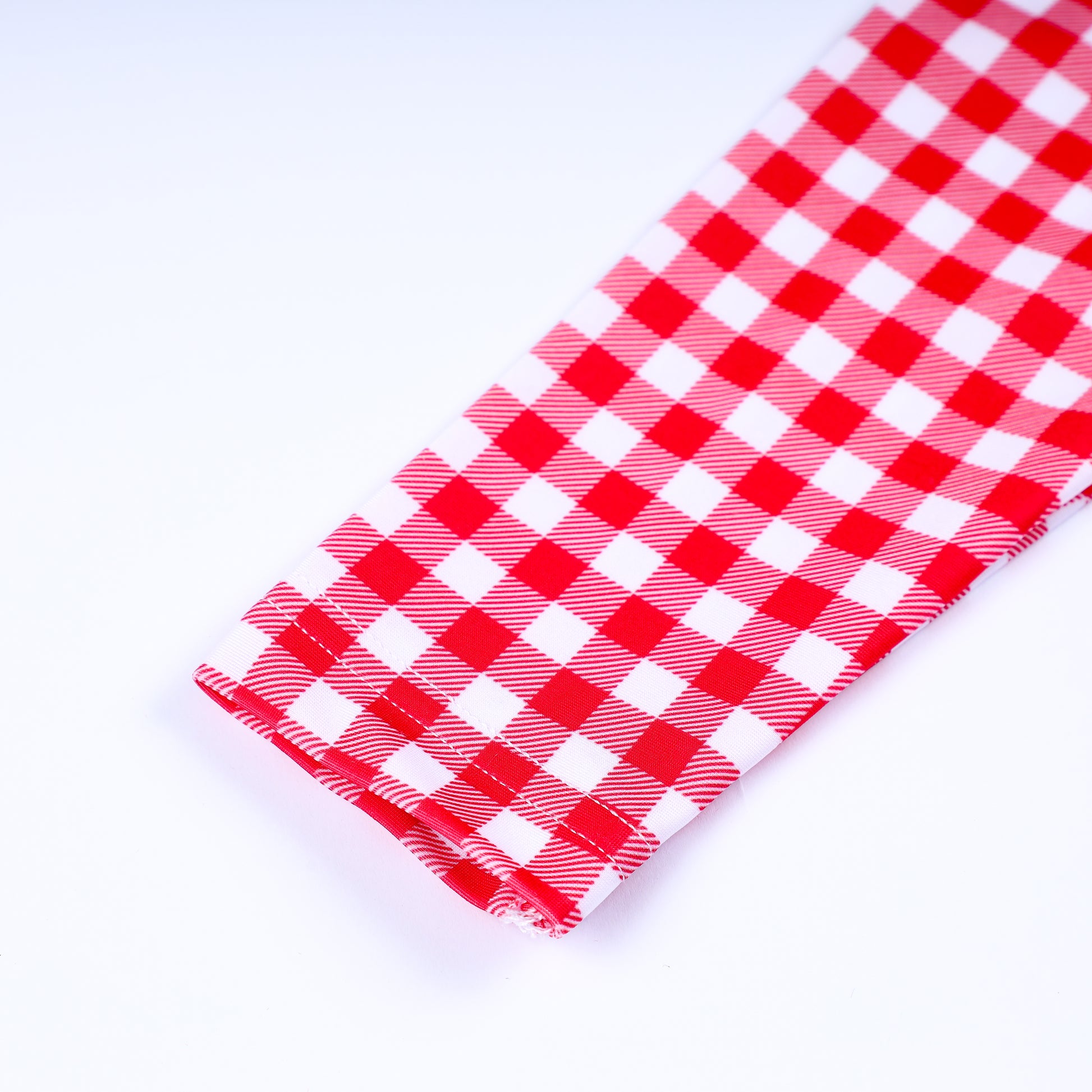 Detailed view of long sleeve cuff stitching on girls red and white gingham checkered rash guard swim top for kids.
