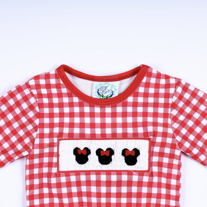 Close-up top view of red gingham long sleeve rash guard shirt with hand smocked Minnie Mouse bow embroidery plate.