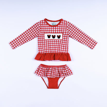 Front view of girls red gingham hand smocked Minnie Mouse two-piece long sleeve rash guard swim set with ruffles.