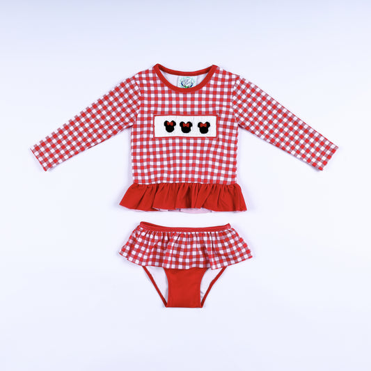 Front view of girls red gingham hand smocked Minnie Mouse two-piece long sleeve rash guard swim set with ruffles.