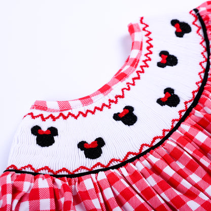 Detailed zoom of white hand smocked neck plate featuring black embroidered mouse icons with red bows on red gingham.