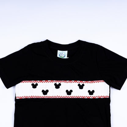 Close-up of hand smocked mouse silhouettes embroidered on white chest plate panel of black boys shirt.