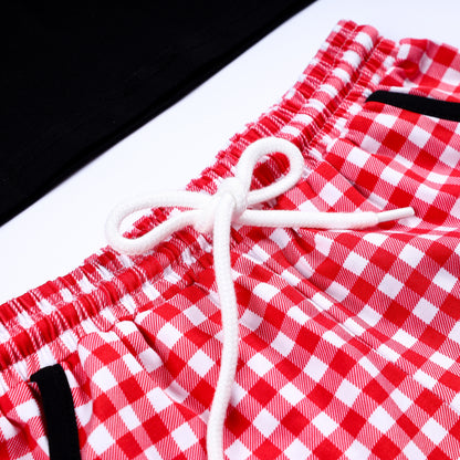 Close-up of white drawstring tie on the elastic waistband of red and white gingham smocked boys shorts.