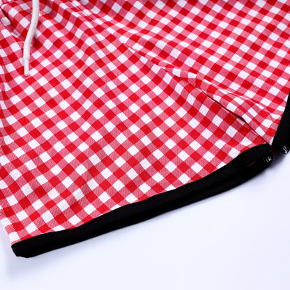 Close-up detail of red gingham check pattern fabric and black hem trim on smocked boys outfit shorts.