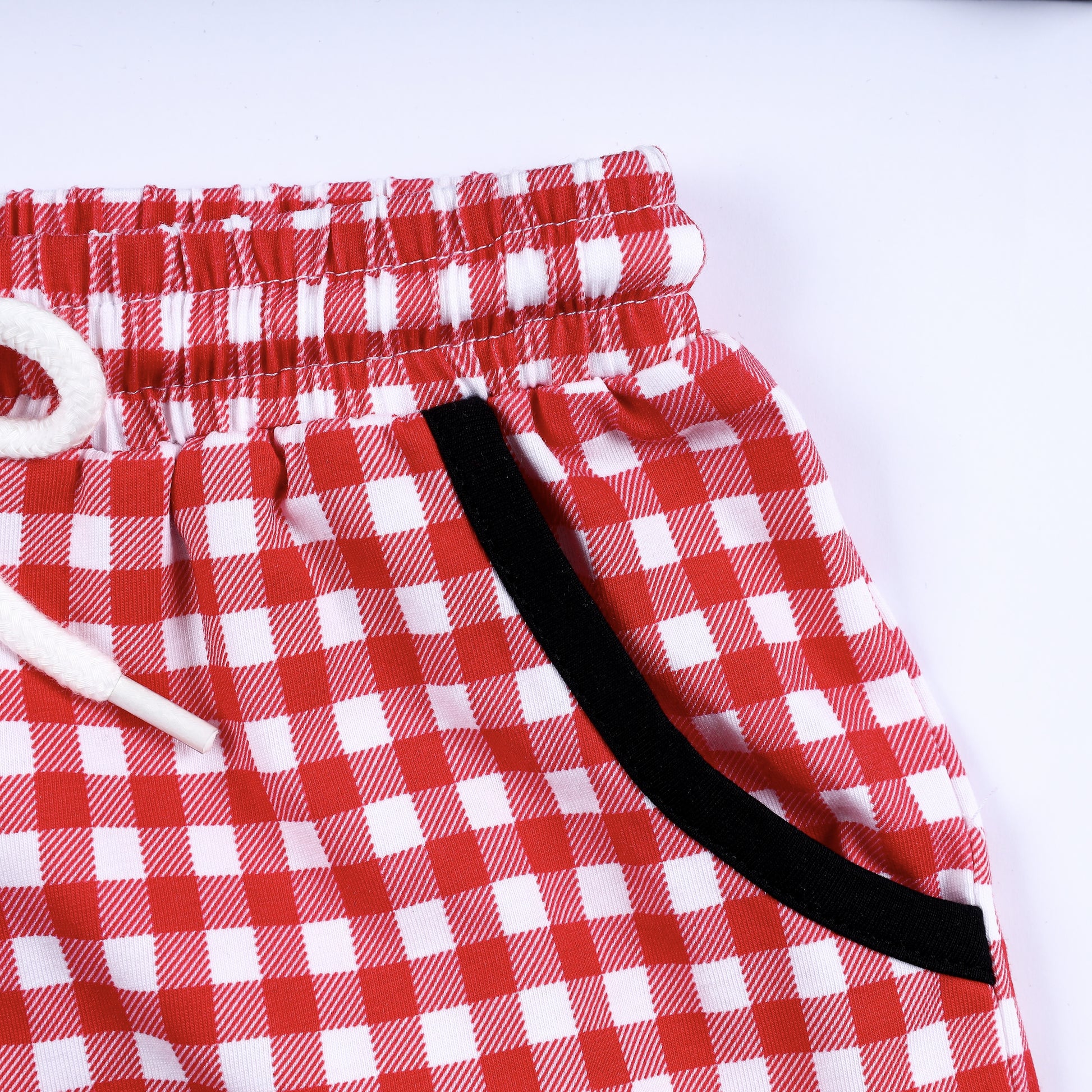 Detailed view of side pocket with black contrast trim on boys red gingham hand smocked shorts set bottom.