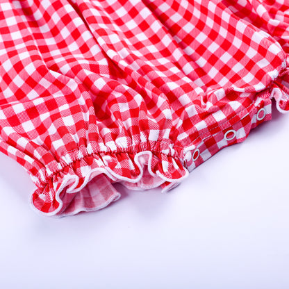 Close up view of elastic ruffled leg openings and convenient snap closure on red gingham smocked bubble romper