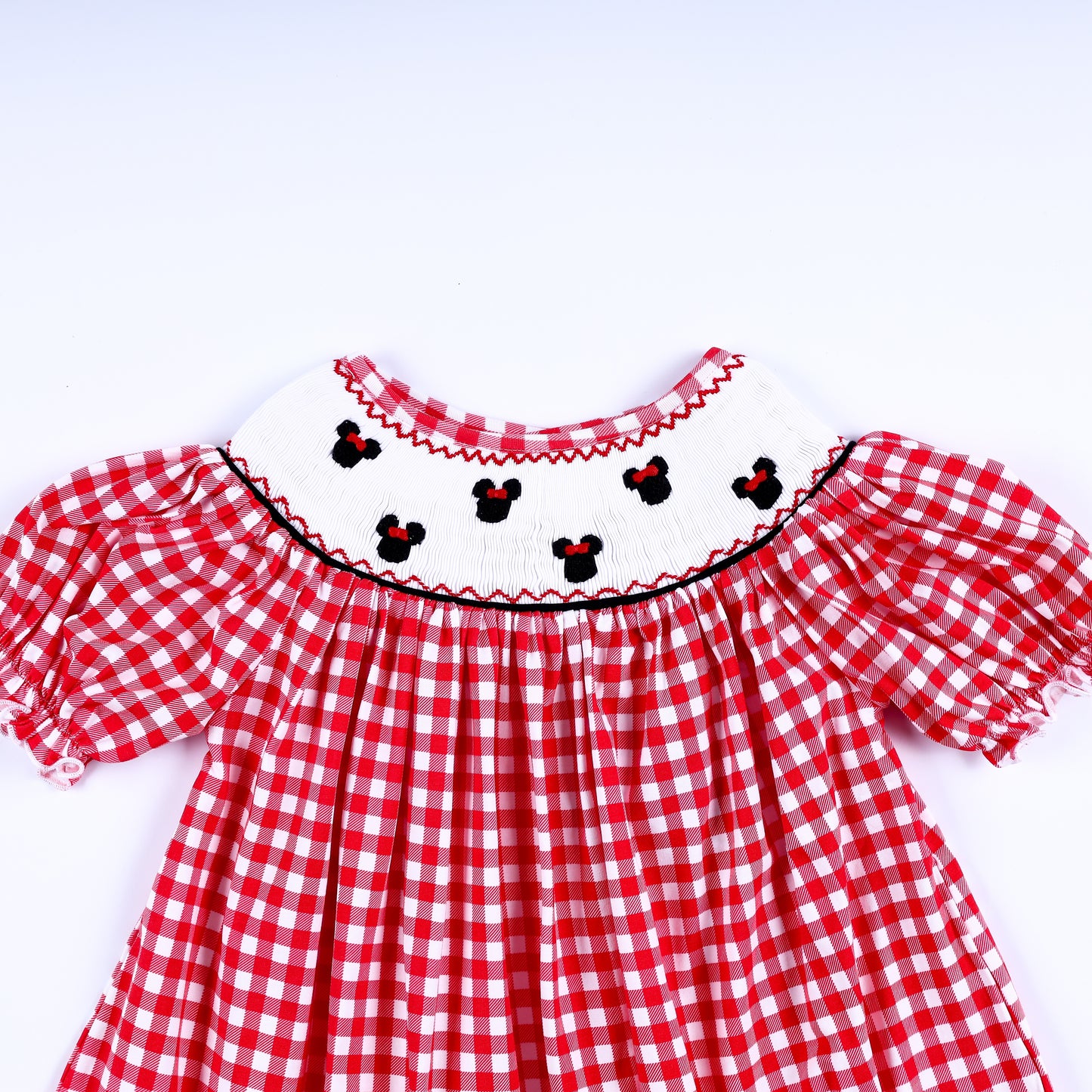 Girls red gingham dress showing the hand-smocked white yoke with embroidered mouse heads and puffed sleeves.