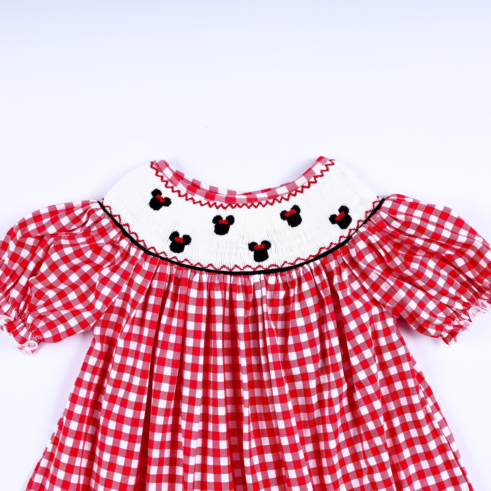 Girls red gingham dress showing the hand-smocked white yoke with embroidered mouse heads and puffed sleeves.