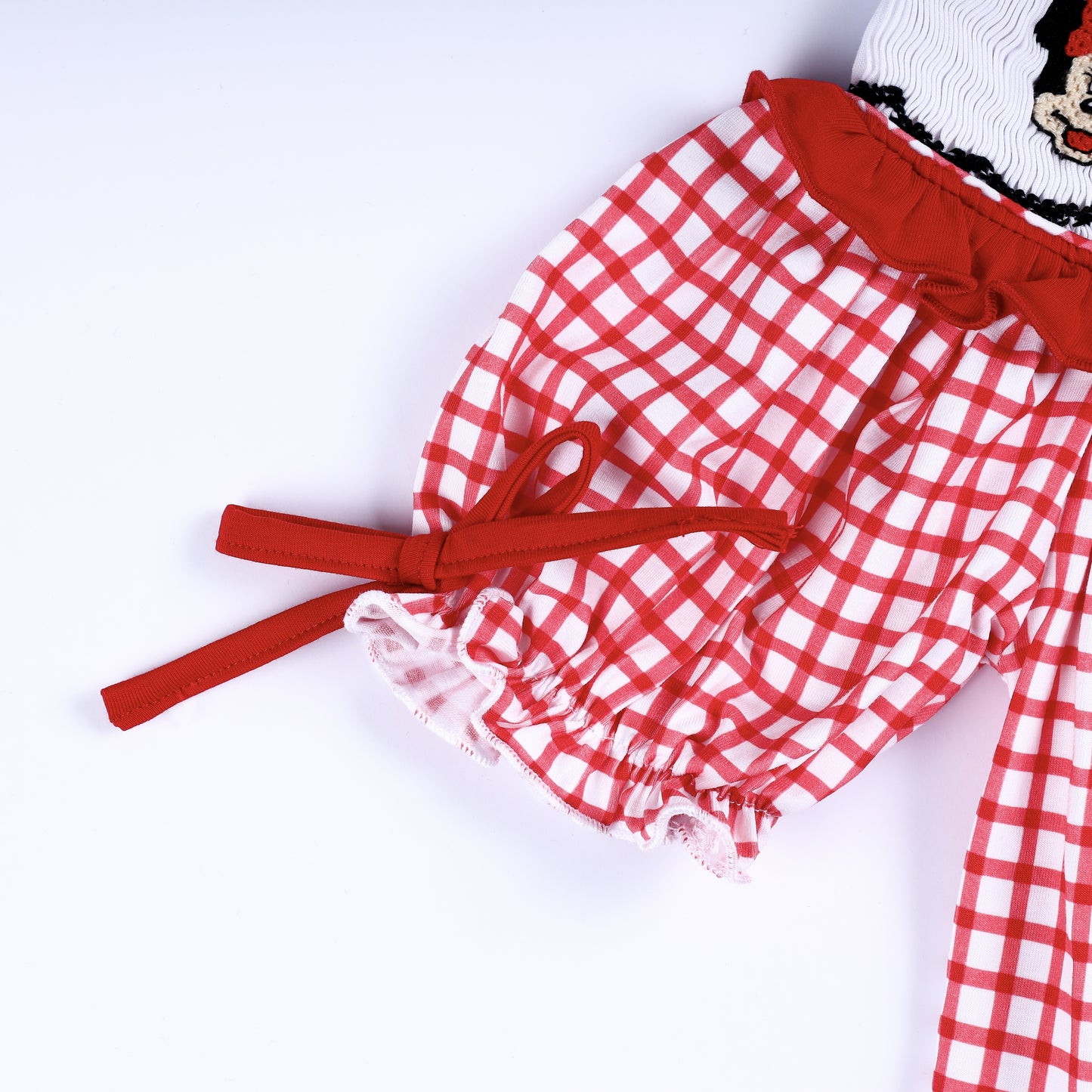 Detail of ruffled puff sleeve with red bow tie on red gingham hand smocked diaper cover bloomer set for girls.