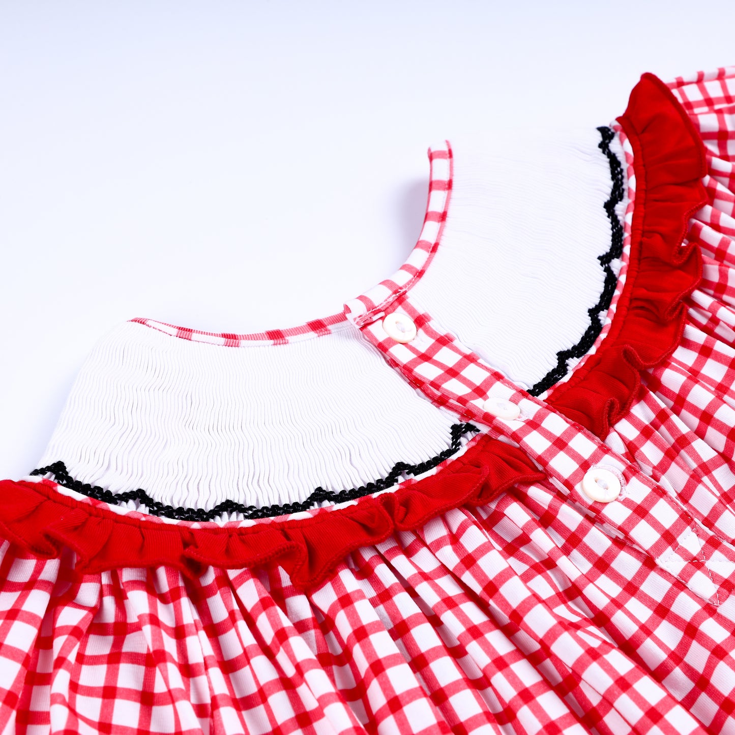 Close up of back button closure and white smocked back collar on red gingham hand embroidered girls dress.