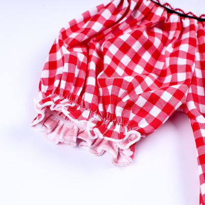Detailed view of the ruffled puff sleeve on a red gingham hand-smocked dress for toddler and young girls.
