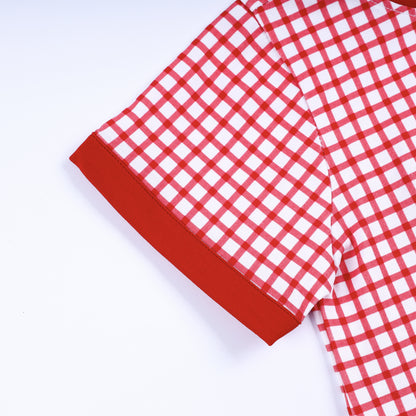 Detailed close up view of red ribbed sleeve cuff and red and white gingham pattern on boys smocked t-shirt.