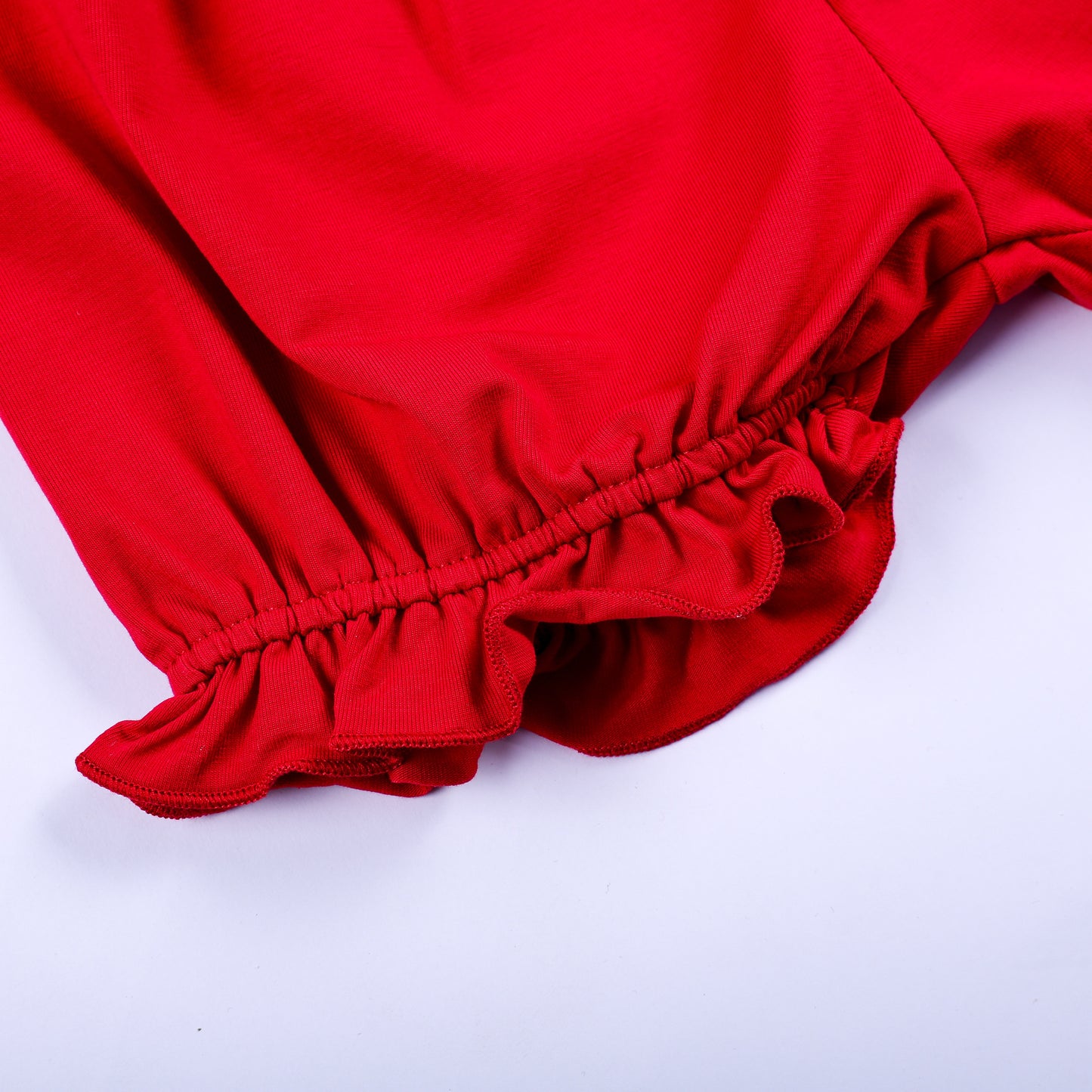 Close-up detail of gathered elastic ruffled cuff on red cotton bloomer shorts for toddler girls set.