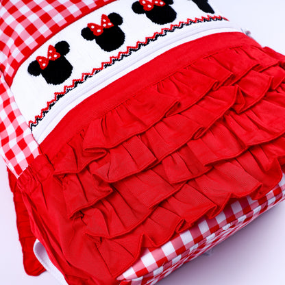 Detailed view of tiered red fabric ruffles on a kids red gingham hand smocked magical mouse backpack.
