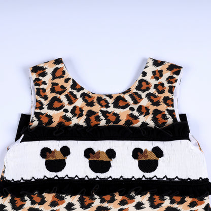 Hand smocked chest panel with embroidered safari mouse ears and black ruffle trim on leopard print top.