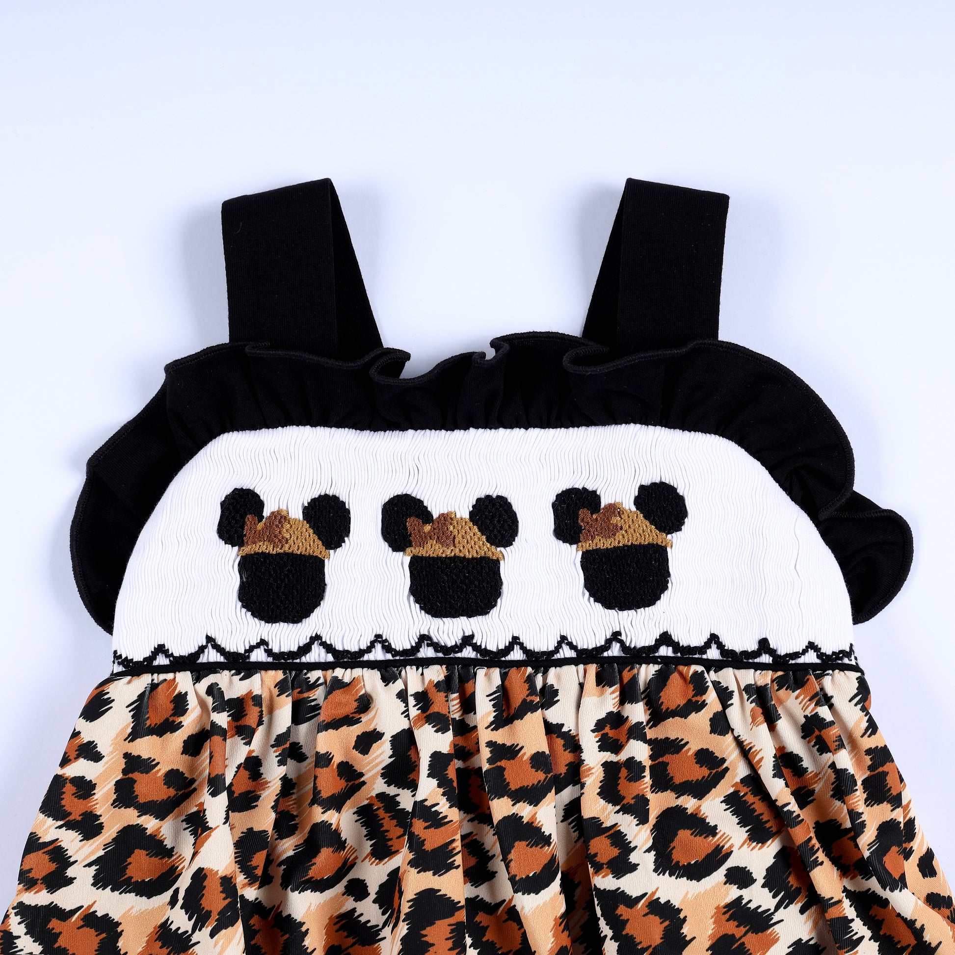 Front bodice smocking with embroidered safari mouse icons on white yoke with black flutter straps and leopard print.
