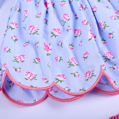 Detail shot of scalloped edge hemline with pink trim on blue floral hand smocked baby girl tunic top.