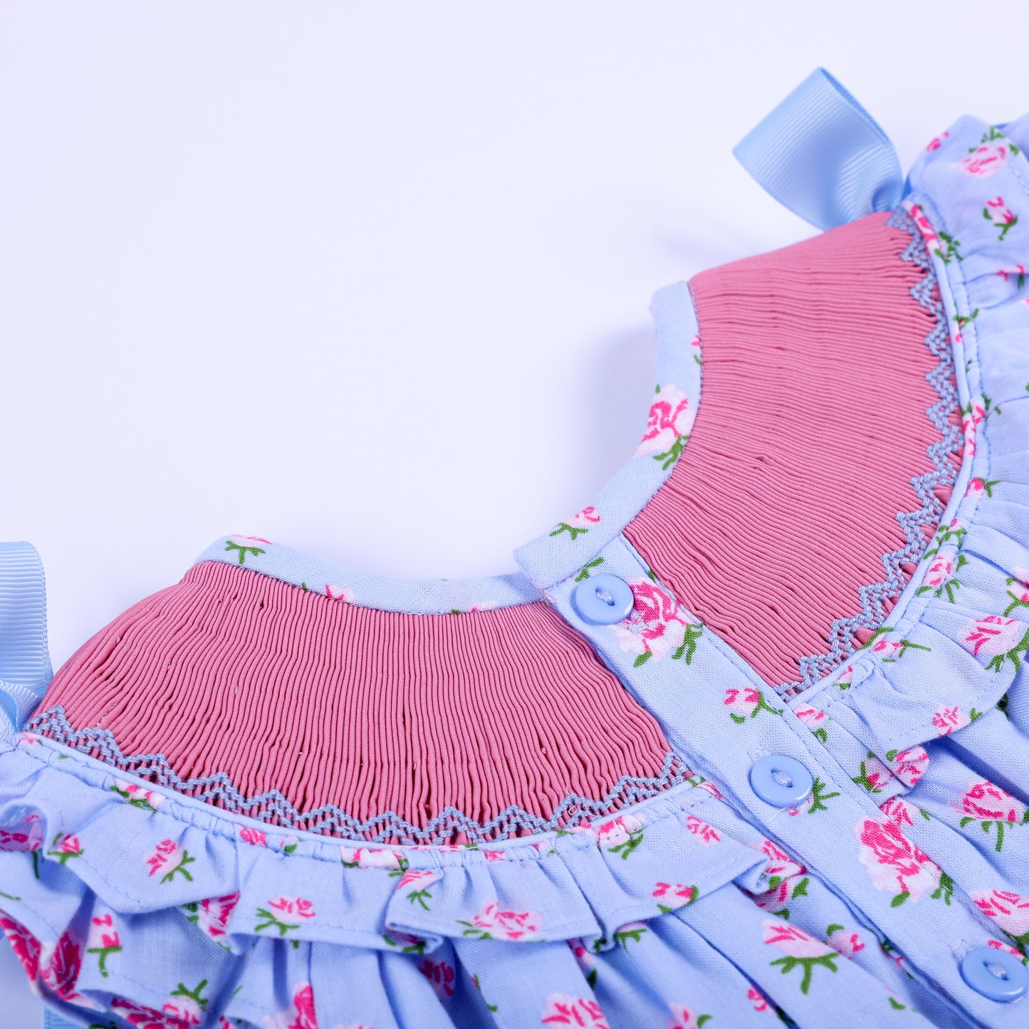 Back collar close-up showing button closures and fine pink smocked yoke detailing on floral baby bubble.