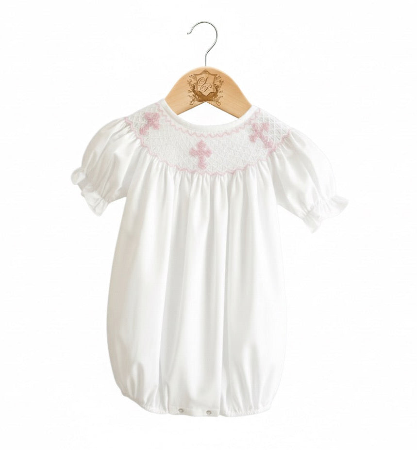 White baby bubble with pink hand smocking and embroidered crosses, featuring 360-degree embroidery.
