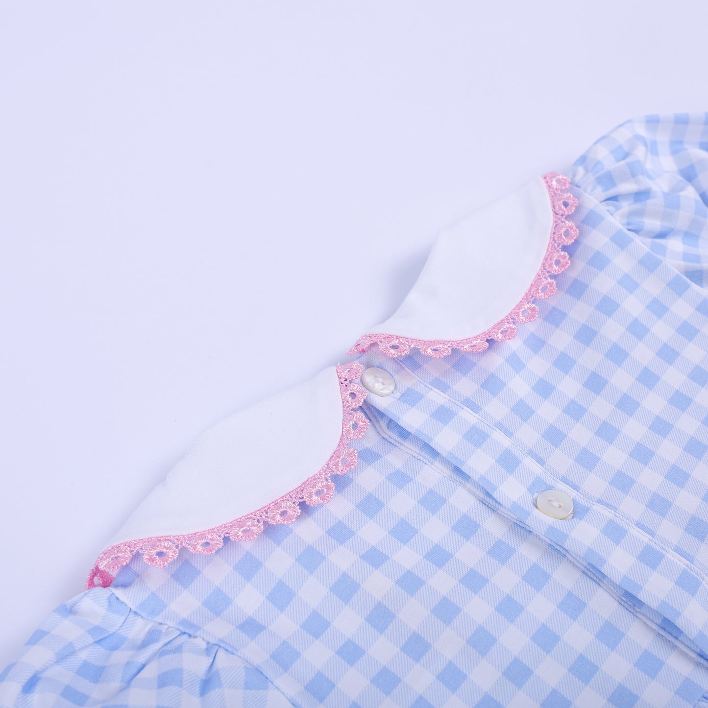 Close-up of the back white Peter Pan collar and button closure on the blue gingham baby shower smocked bubble romper.