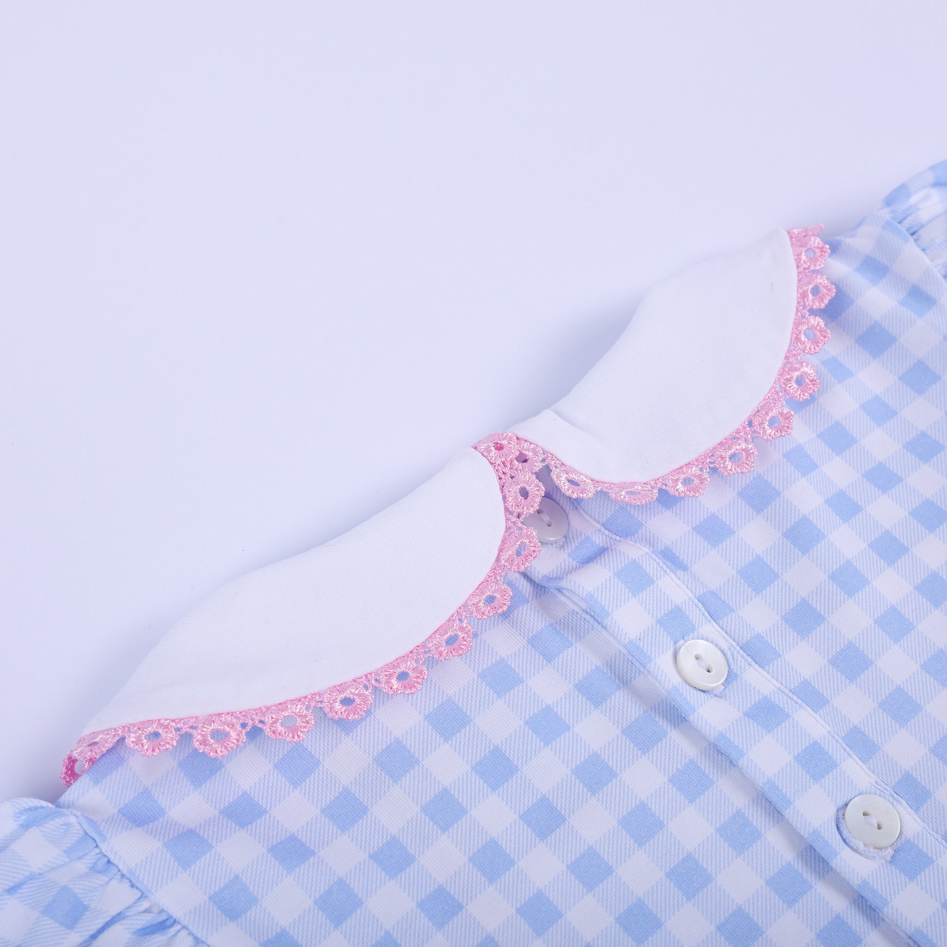 Close up of back neckline on gingham baby dress showing button closure and scalloped pink trim on Peter Pan collar.