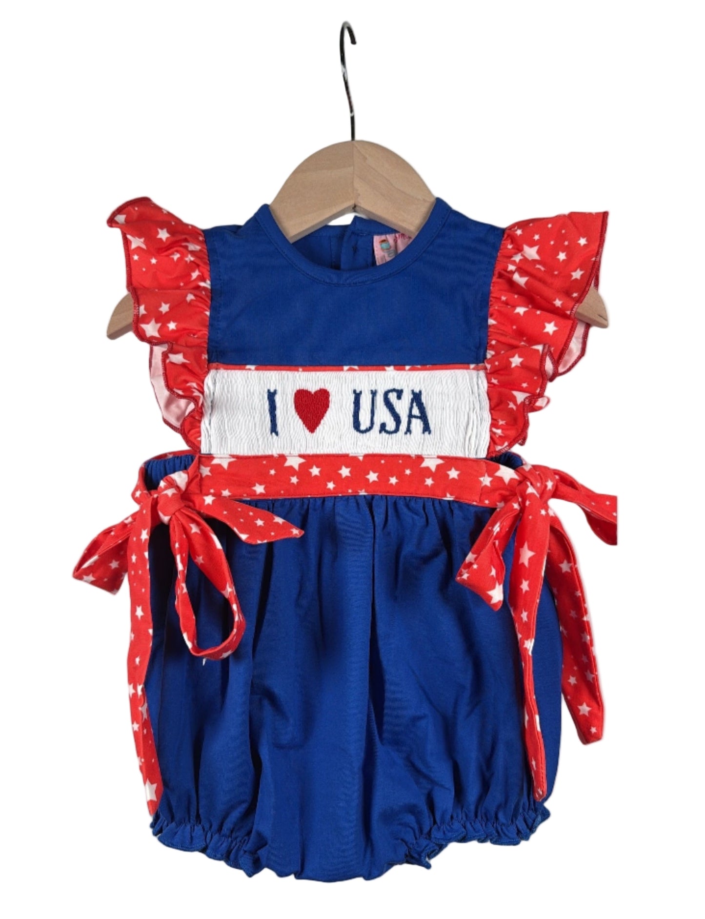 Hand smocked "I Love USA" patriotic bubble romper for baby girls, featuring red, white, and blue stars and ruffles.