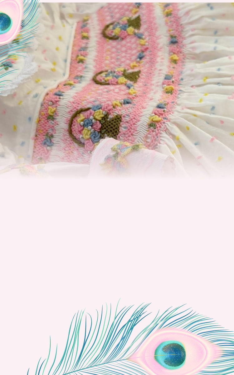 A close-up of a pink embroidered textile with floral and paisley-style stitching, white ruffled trim.
