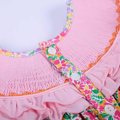 Macro view of the white buttons and intricate pink smocked details on the back of the girls Thanksgiving floral tunic.