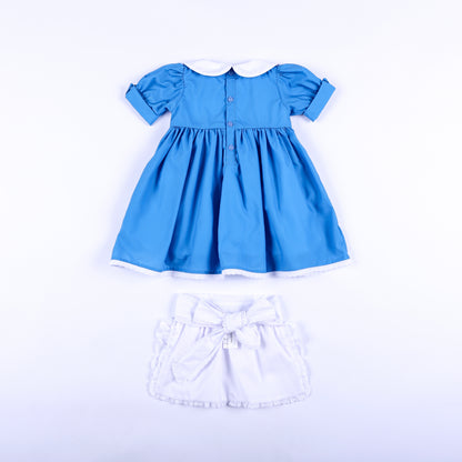 Back view of storybook wonderland blue dress with button back and white embroidered apron with bow tie.