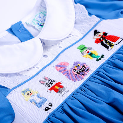 Detailed hand smocked and hand embroidered bodice featuring fairytale characters on blue girls dress.