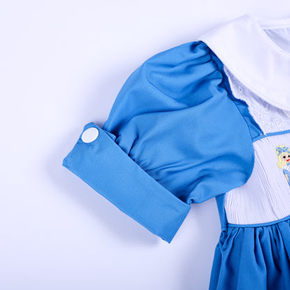 Close-up detail of puffed short sleeve with white button cuff on a blue hand smocked storybook dress.