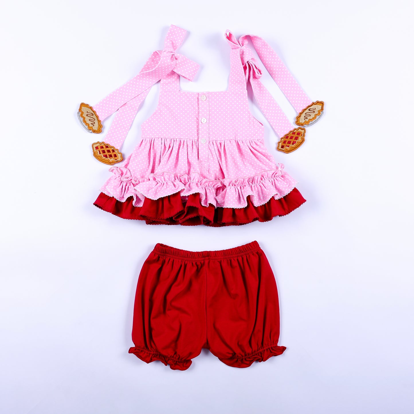 Back view of girls pink polka dot top with red bloomer shorts showing button closure and strap bows.