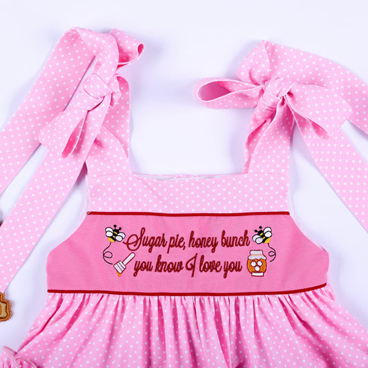 Close-up of pink polka dot embroidered top bodice with shoulder bows and Sugar Pie Honey Bunch quote.