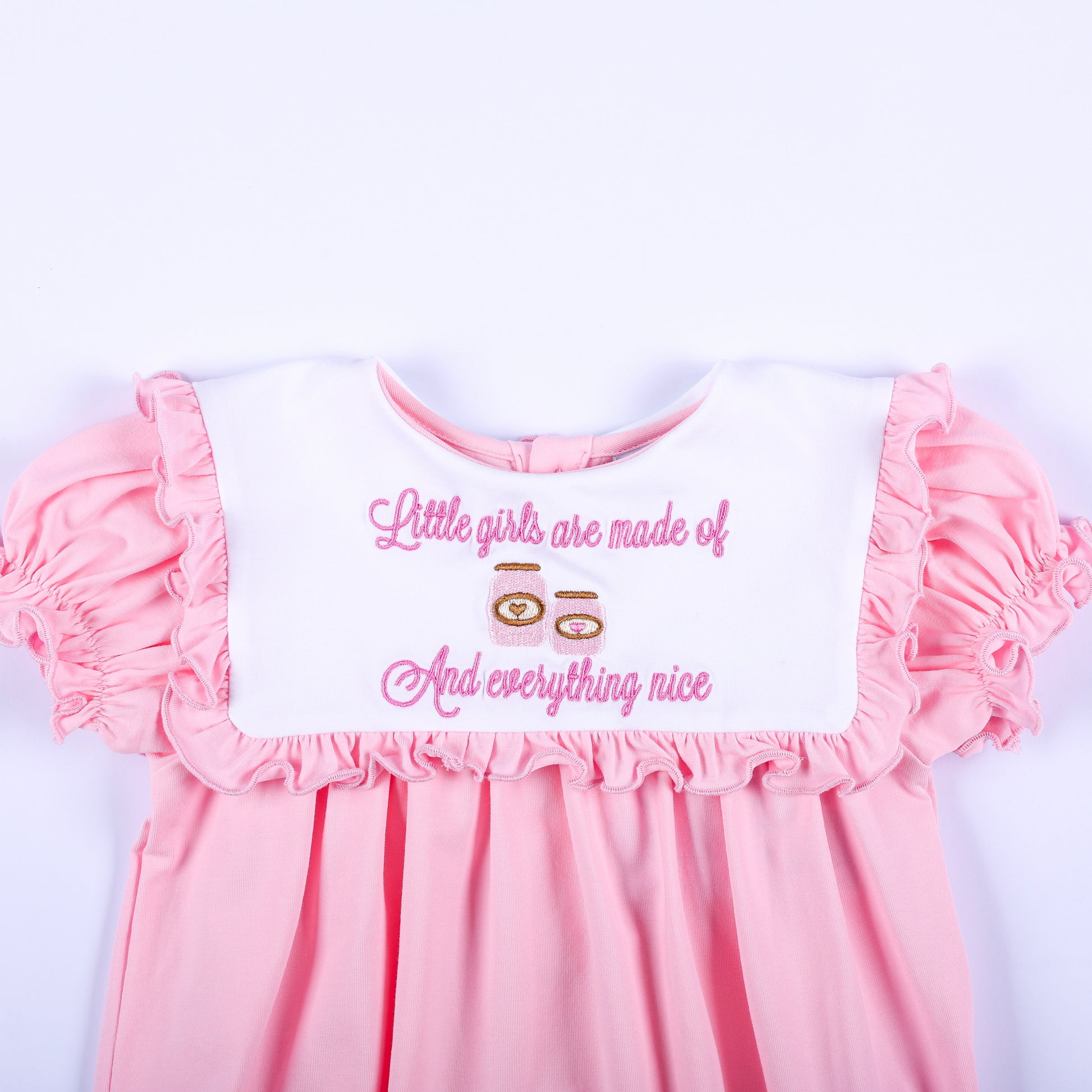 White ruffled collar embroidered with pink sugar and spice everything nice text on a baby girl pink bubble romper.