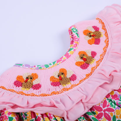 Close-up detail of the pink smocked ruffled collar with hand-embroidered Thanksgiving turkeys on a baby bubble romper.