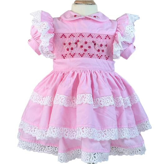 Pastel pink vintage Valentine heirloom dress featuring hand-smocked red hearts, embroidered rosebuds, and lace-trimmed tiers by Smocked Peacock.