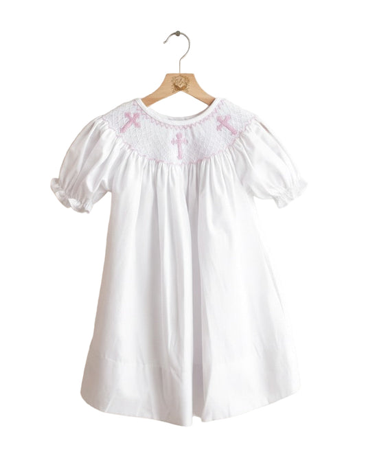 White smocked girls christening dress with puff sleeves and three pink embroidered crosses on the yoke.